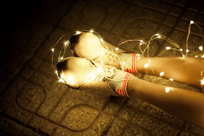 Feet in cozy knit socks wrapped in strands of warm white fairy lights