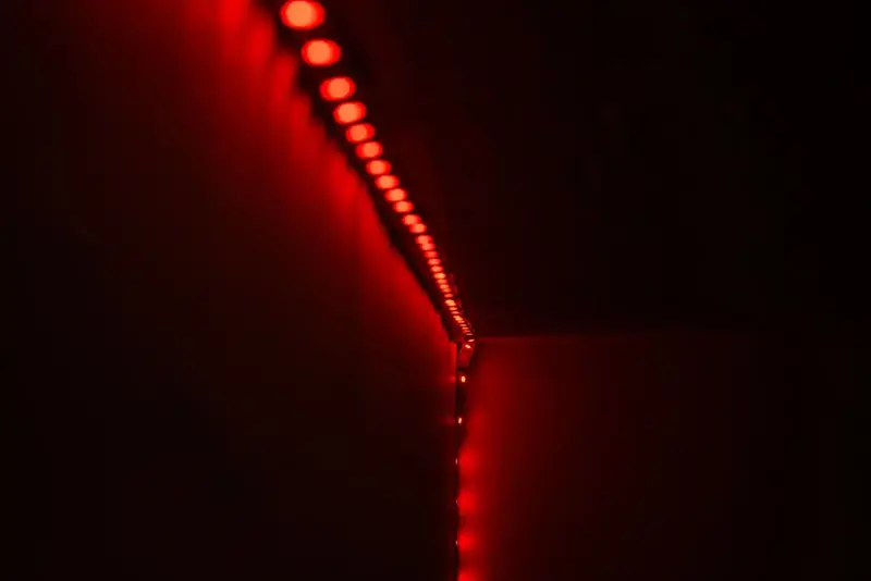 Red LED strip lights glowing along a ceiling edge in a dark room