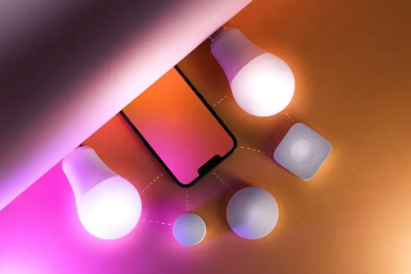 Smart color bulbs glowing pink next to a smartphone